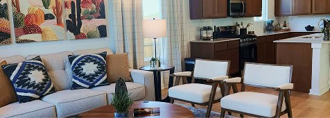 Living room with sofa, chairs, and kitchen in Fika community in Elgin TX.
