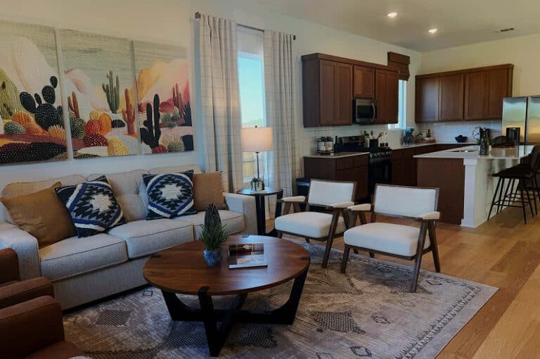 Living room with sofa, chairs, and kitchen in Fika community in Elgin, TX.