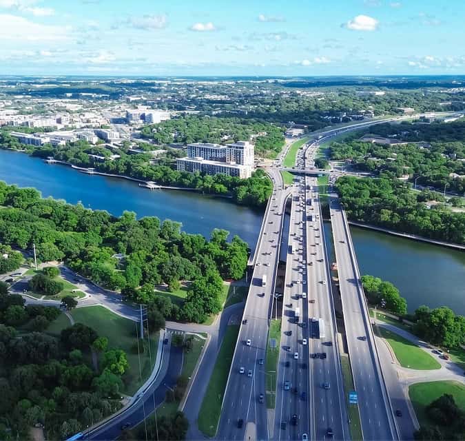 Aerial view of a bridge over a river in Elgin, TX with surrounding greenery.