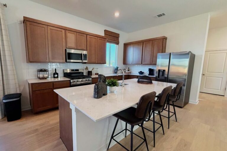 Modern kitchen with island and wooden cabinets in Fika community.
