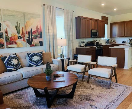 Living room with sofa, chairs, and kitchen in Fika community in Elgin, TX.